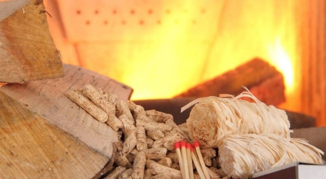Das Bild zeigt Holzscheite und Pellets mit Anzündhilfen vor dem Kamin. Das Bild zeigt Holzscheite und Pellets mit Anzündhilfen vor dem Kamin.