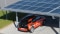 Das Bild zeigt ein Carport mit PV-Modulen auf dem Dach und ein Elektroauto, das gerade aufgeladen wird. 