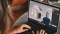 Das Bild zeigt eine Person, die an einem Laptop an den online Classrooms teilnimmt.