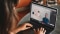 Das Bild zeigt einen geöffneten Laptop mit erklärender Person auf dem Bildschirm. 