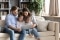 Eine Familie sitzt gemütlich auf einem Sofa und schaut gemeinsam auf ein Tablet
