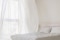 Das Bild zeigt ein Schlafzimmer mit geöffnetem Fenster und wehenden Vorhängen.    